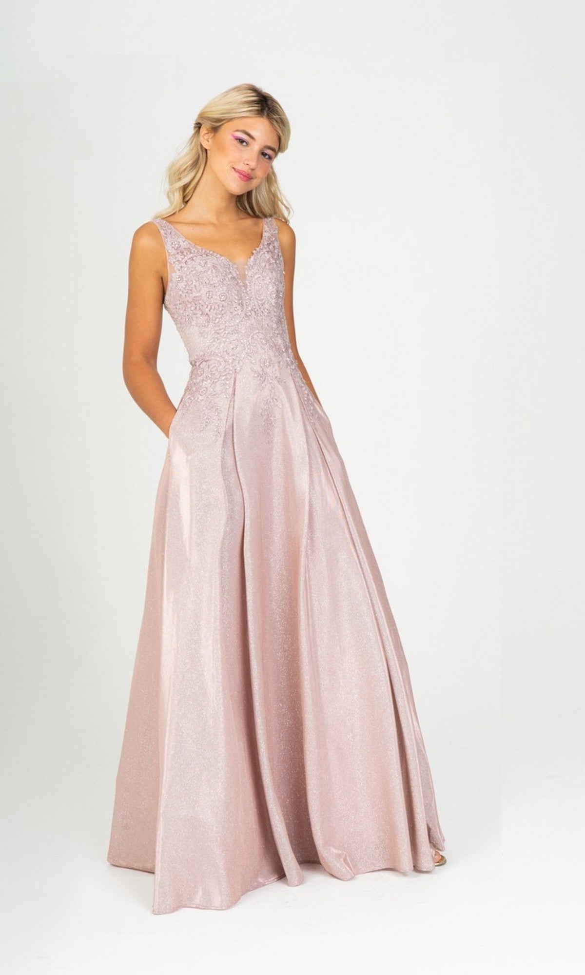 A woman stands wearing the Eureka 9606 long prom dress in champagne, featuring a sleeveless embroidered bodice and a flowing, floor-length A-line skirt.